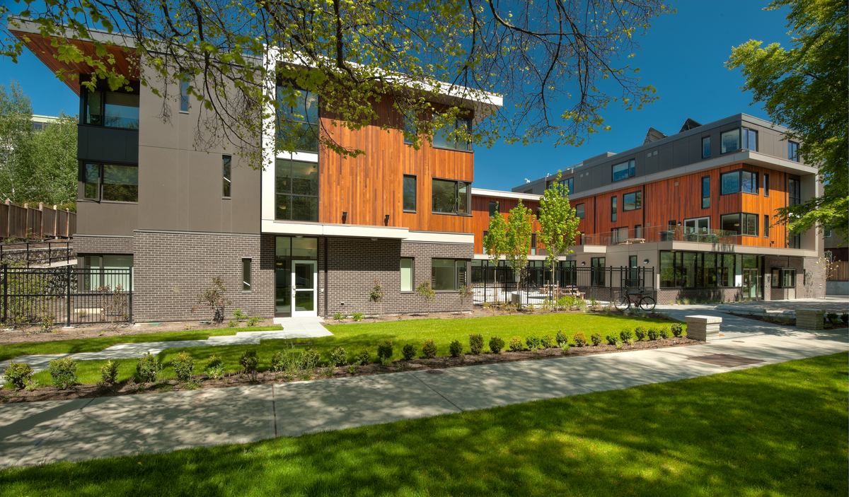Exterior sunny view of three-storey low rise mass timber constructed Camas Gardens Supported Housing showing warm exterior of Western Red Cedar