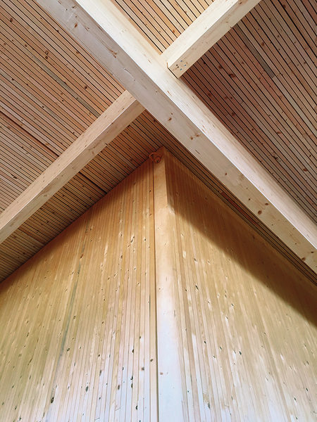 Upward view of dowel-laminated timber (DLT), a mass timber product, showing crossing and notched DLT beams supporting wood roof above