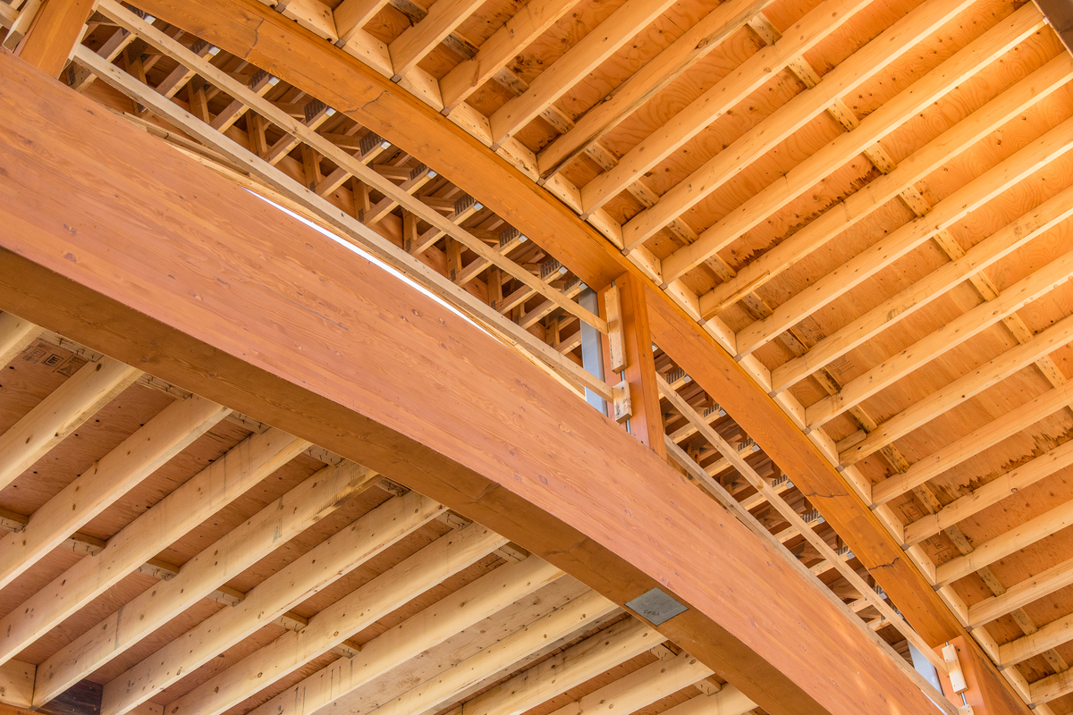 Interior daytime close up view of Tsleil Waututh Administration and Health Centre roof joinery showing major arched glue-laminated timber (Glulam) bean supporting wooden trusswork and rafters